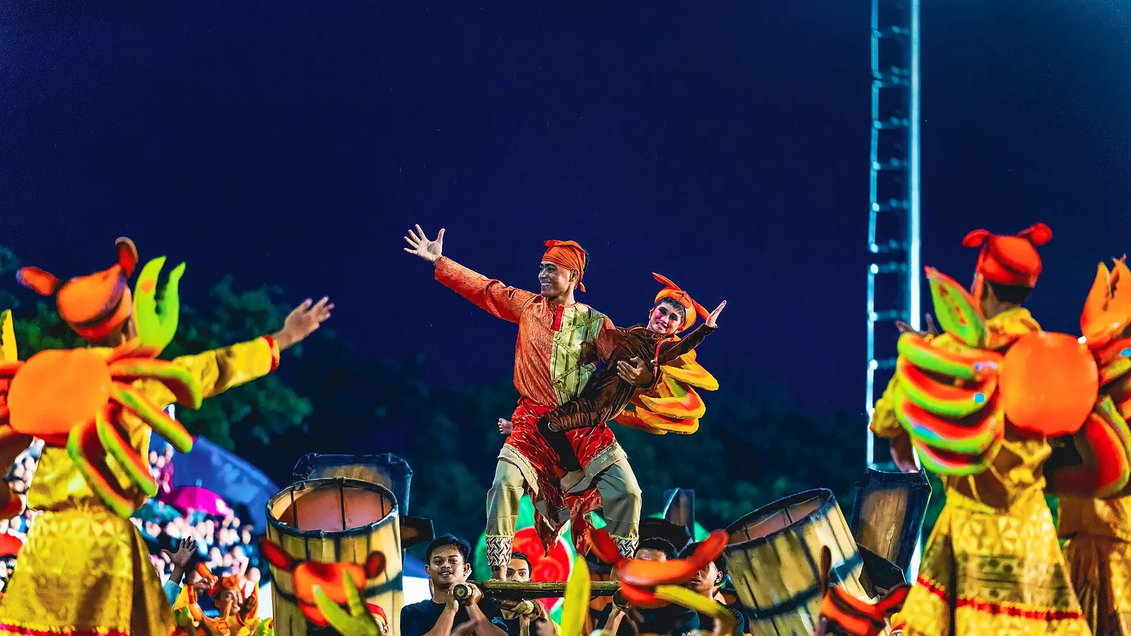 A Buglasan Festival street dancer in Dumaguete lifted overhead in an orange and gold crab-themed costume during the night parade