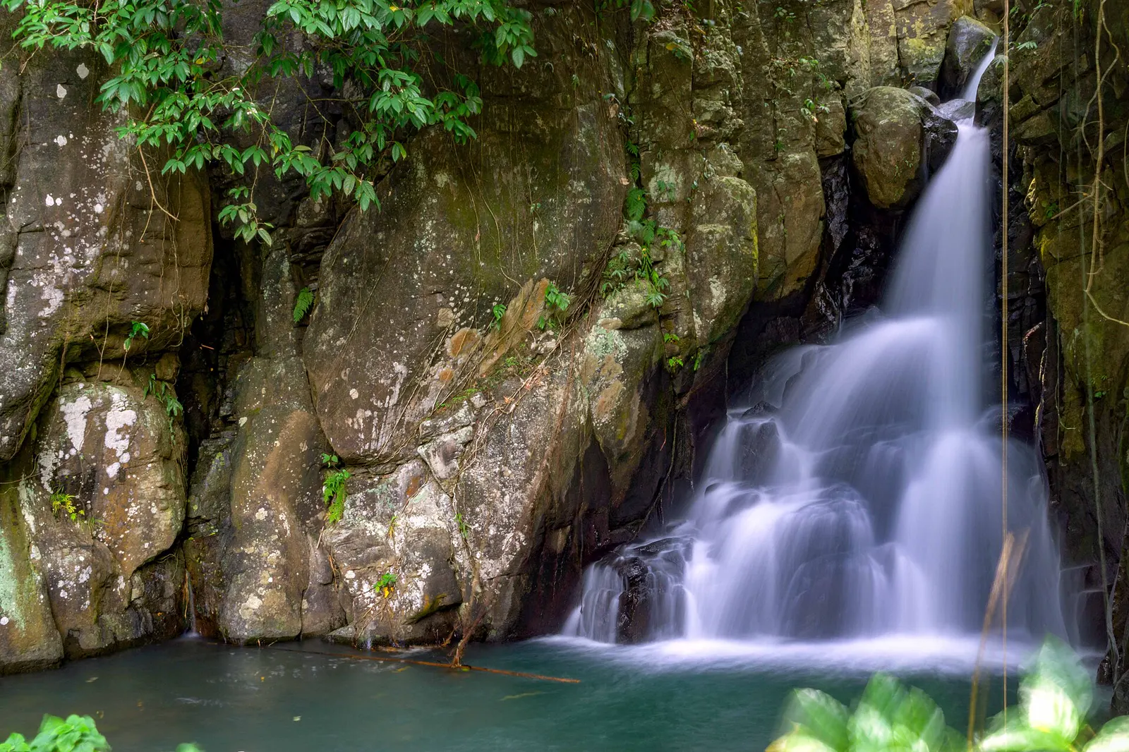 A forest waterfall spilling into a green pool on the seven-falls trail at Mambukal Resort, Murcia, Negros Occidental