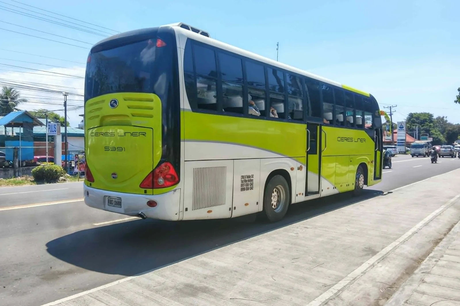 A lime-green and white Ceres Liner coach of Vallacar Transit on a two-lane highway